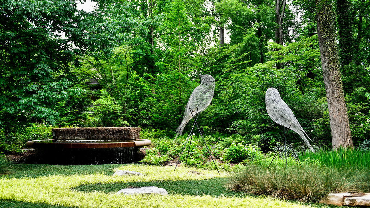 The image shows the iconic "Luminous Wire Birds" sculpture installation by French artist C&eacute;dric Le Borgne