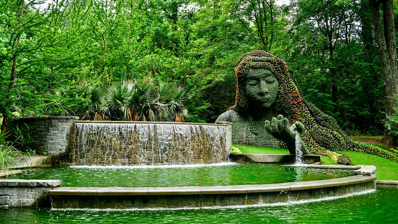 The image shows the iconic Earth Goddess (sometimes called "Mother Earth" or "Gaia"), a massive 25-foot-tall living plant sculpture in the Cascades Garden.