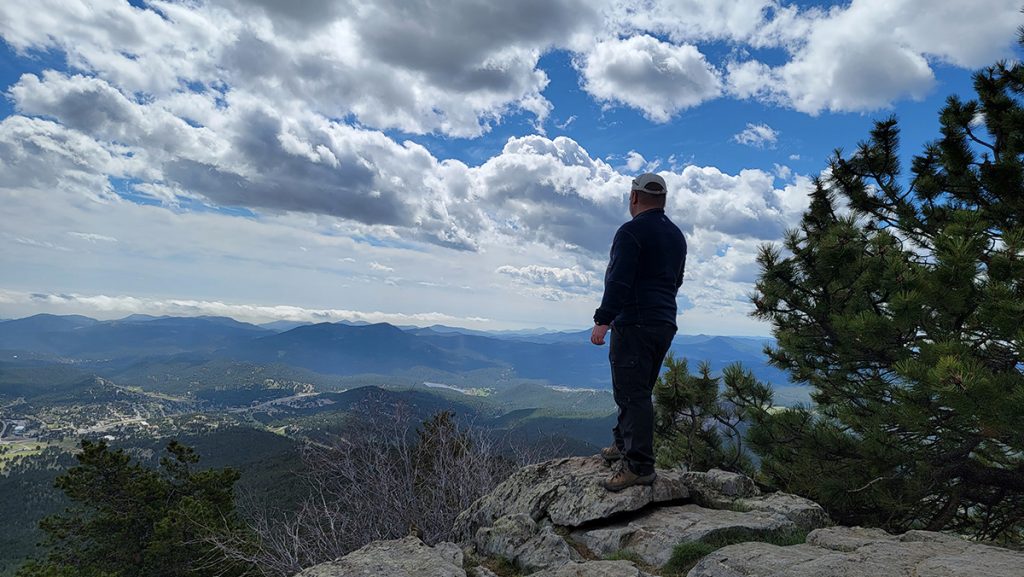 man in K&Uuml;HL clothing standing on the overlook during daytime