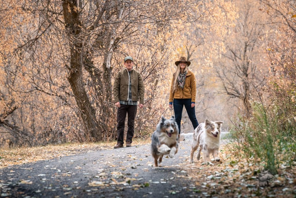 man and woman in K&Uuml;HL jackets watching two dogs
