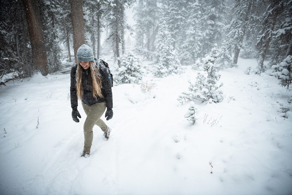 woman in K&Uuml;HL clothing walking on snowy path in the forest